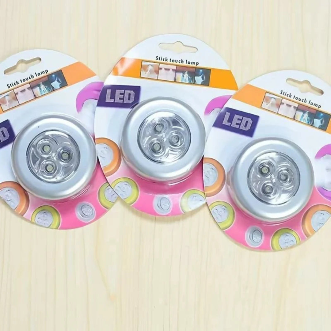 Three packaged stick touch LED lamps arranged side by side on a light wood surface. Each lamp is mounted on a colorful blister card with the text 'LED' and 'Stick touch lamp' visible.