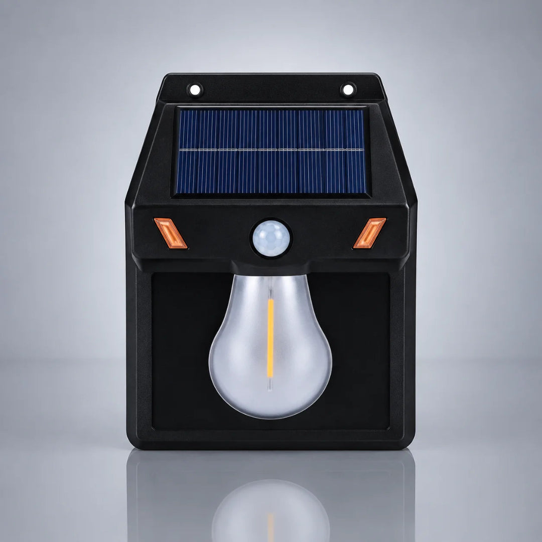 A black solar-powered outdoor security light with a blue solar panel, motion sensor, and a large bulb-shaped LED light, shown on a reflective gray background.