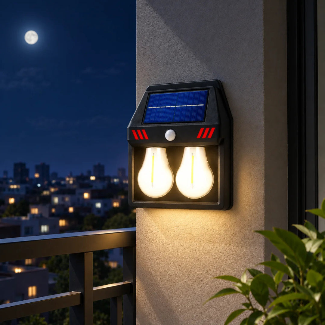 Solar outdoor wall light with two glowing bulbs, mounted on a beige stucco wall at night with a city skyline and moon visible in the background.