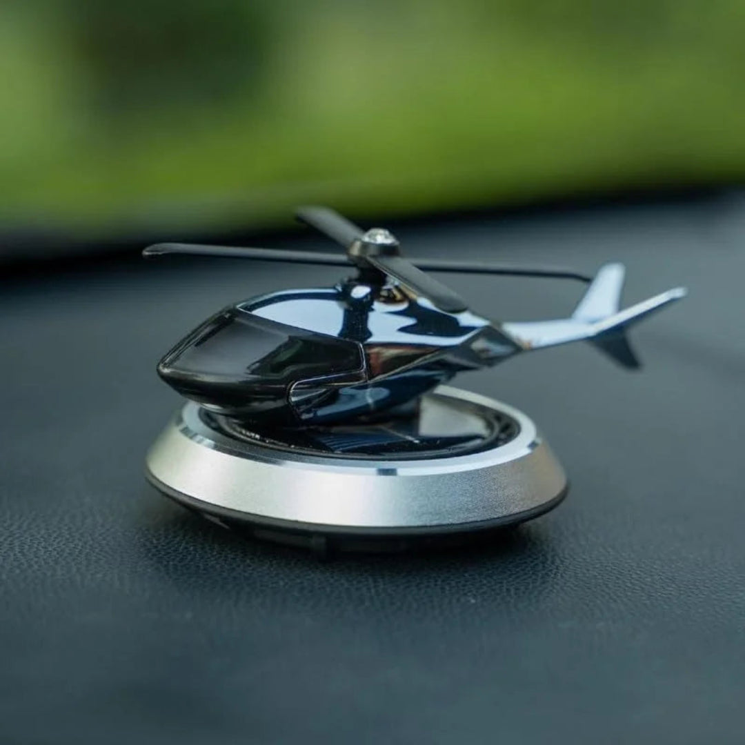 Metallic helicopter model on a reflective surface with a blurred green background
